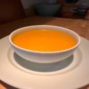 Creamy carrot soup in a white bowl.