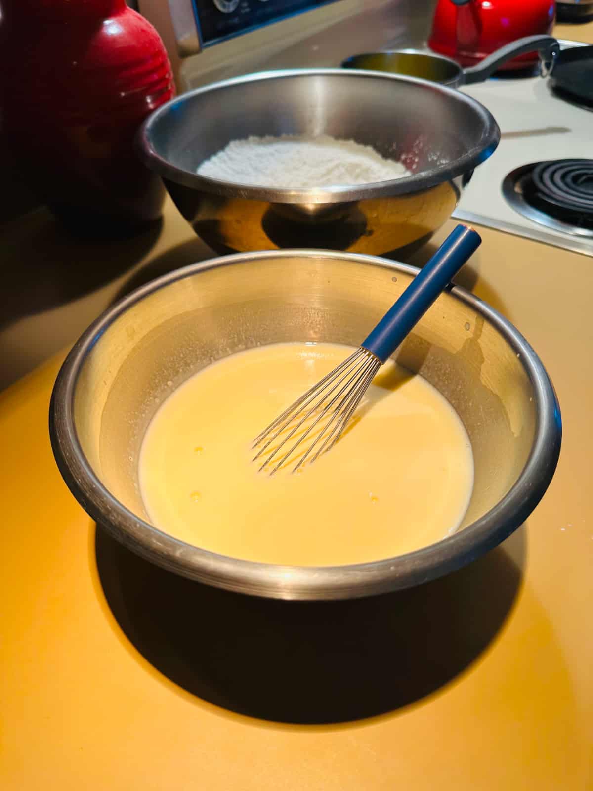 Buttermilk and eggs in a steel bowl with a whisk.