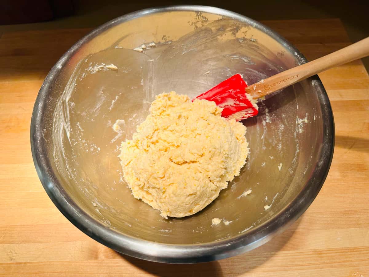 Dumpling batter in a steel bowl with a red rubber spatula.