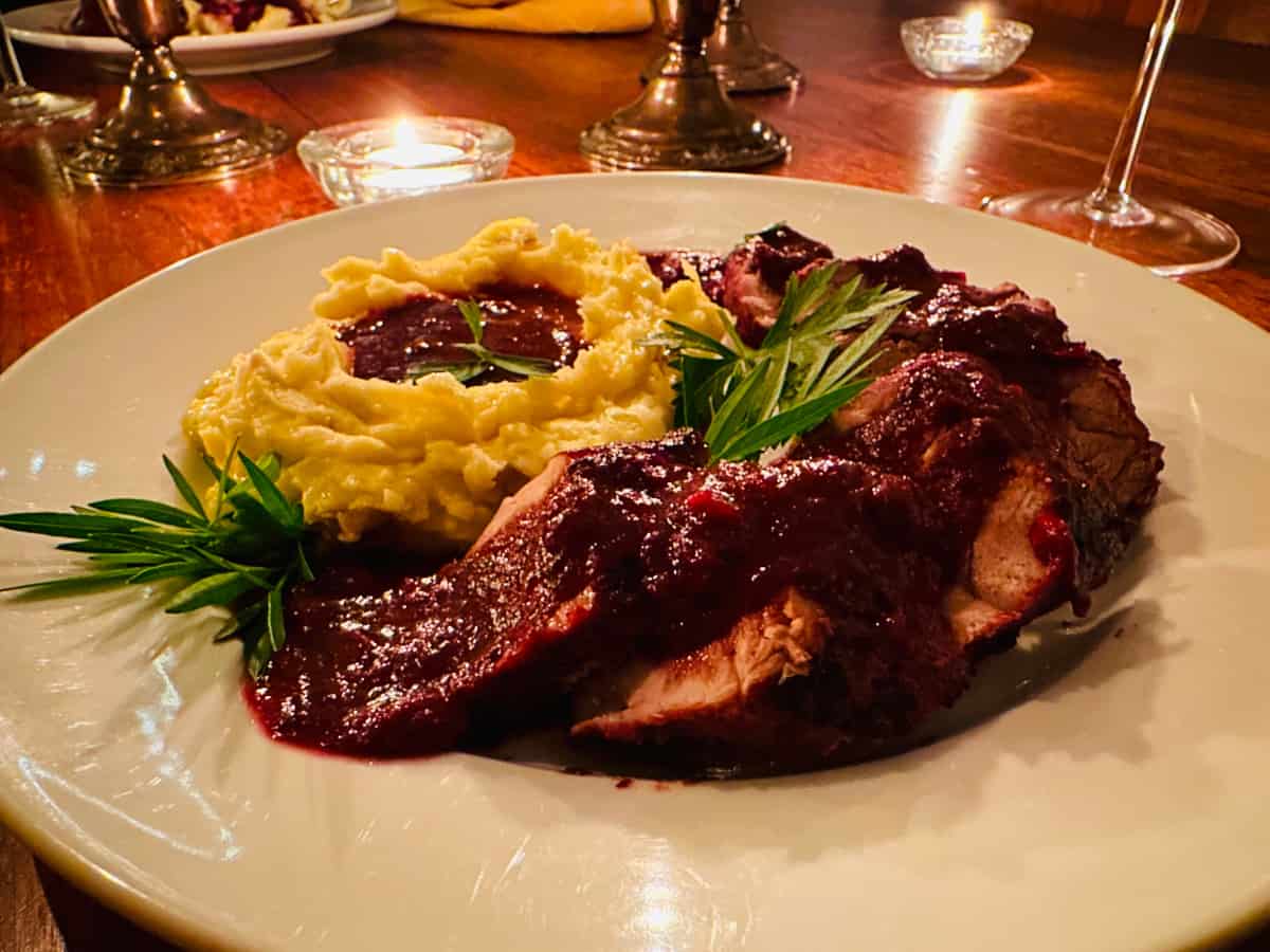 Pork tenderloin with lingonberry gravy and mashed potatoes on a white plate.