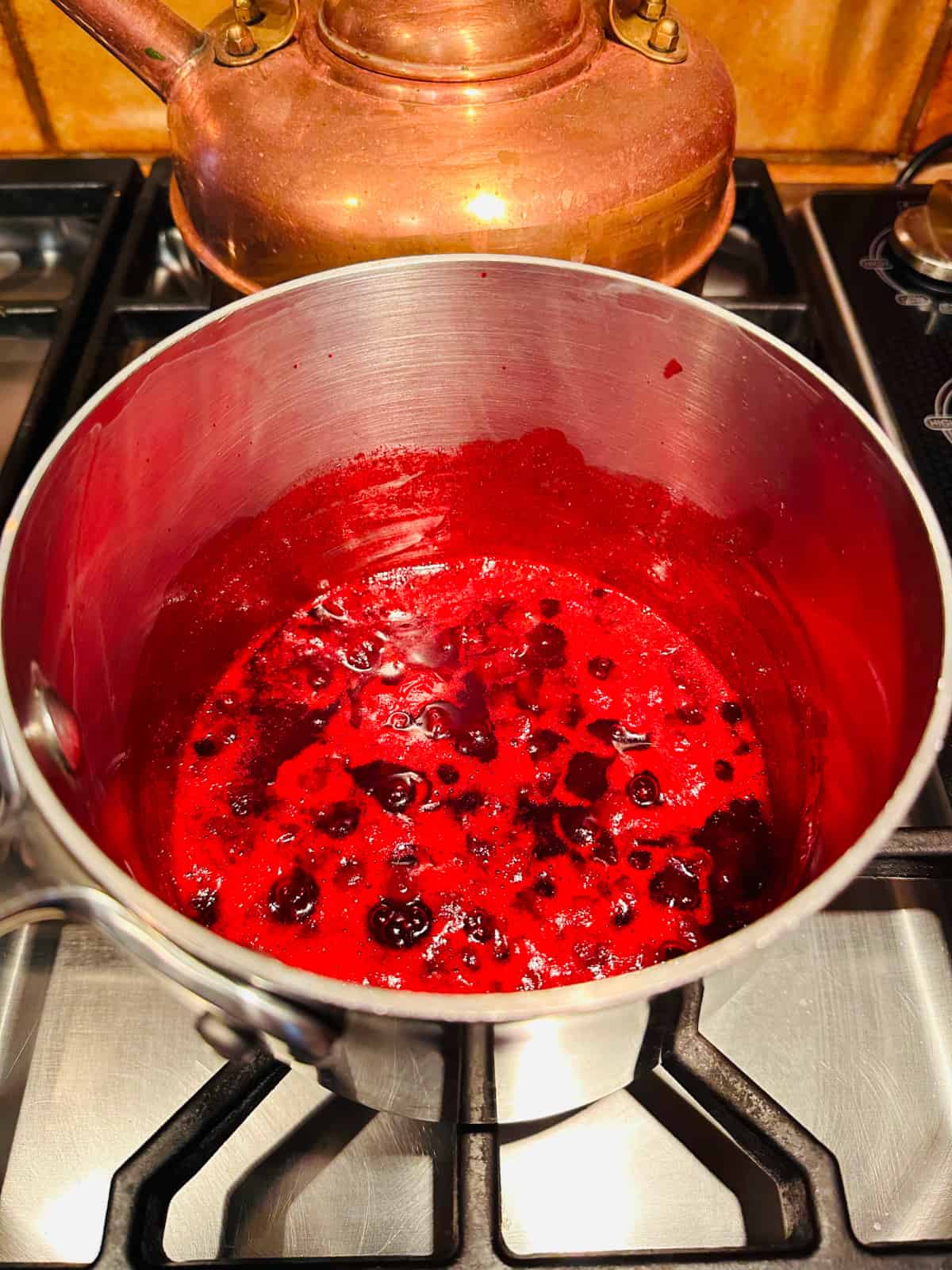 Lingonberries simmering in a small saucepan.