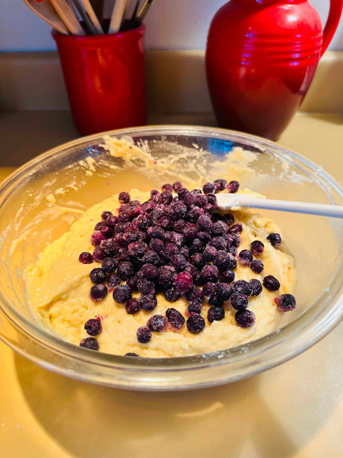 Muffin batter with berries added in a glass bowl.