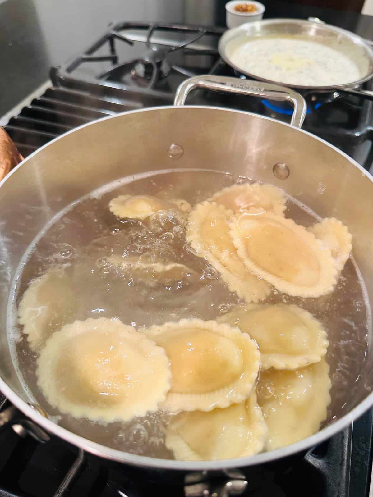 Ravioli cooking in a steel pot of boiling water.