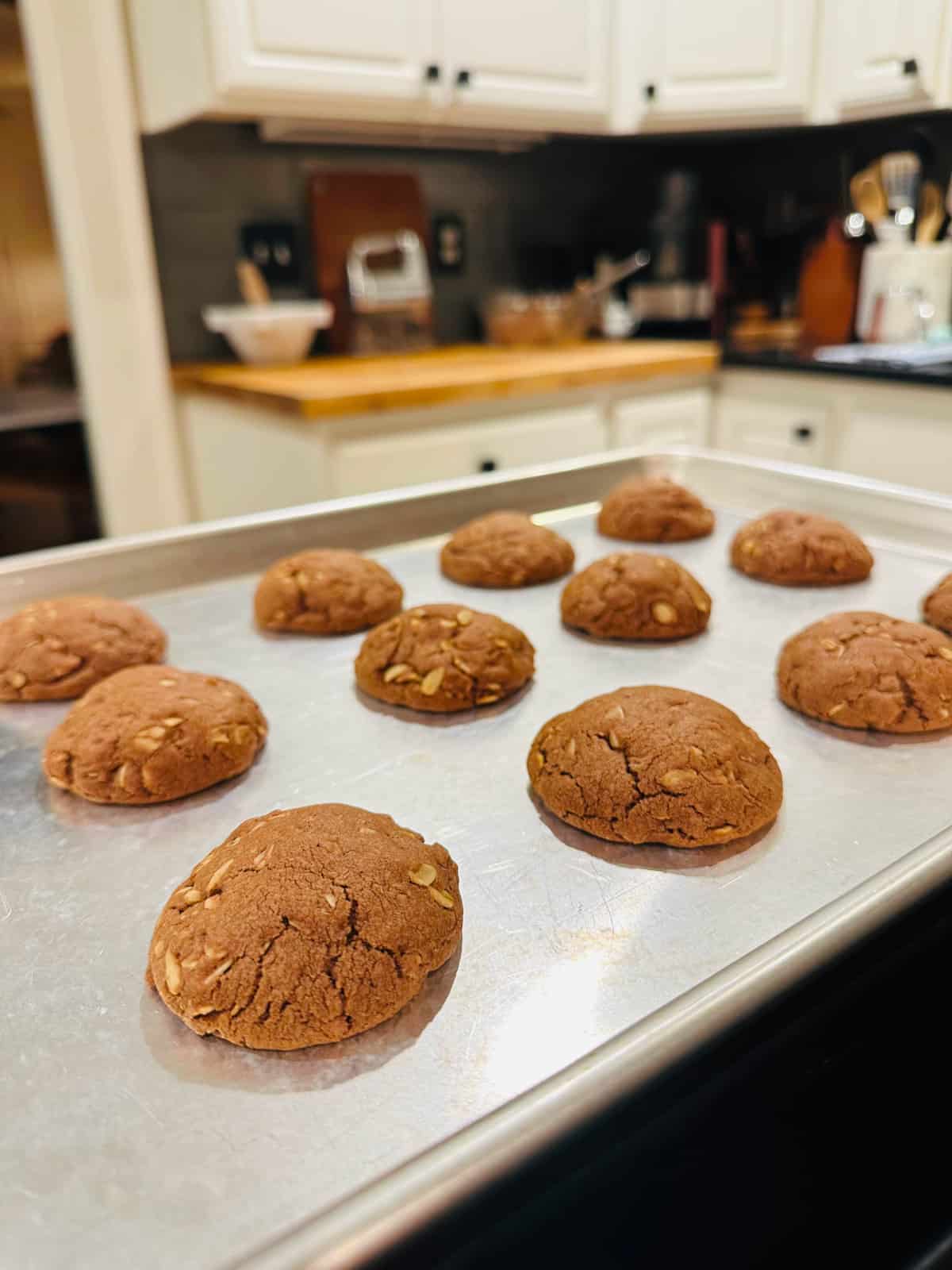 Baked chocolate oatmeal cookies on metal baking sheet.