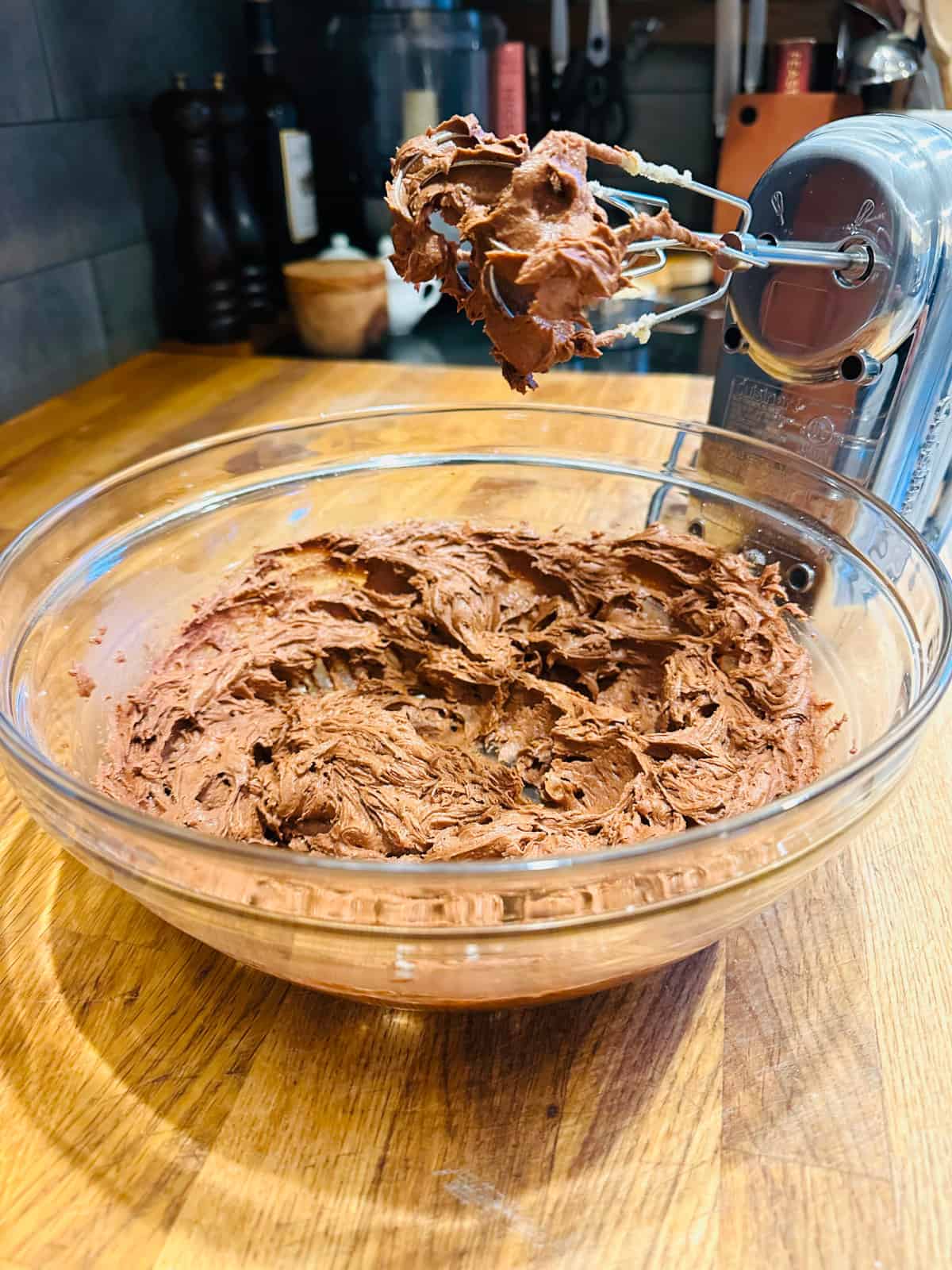 Glass bowl of chocolate oatmeal cookie batter next to electric mixer