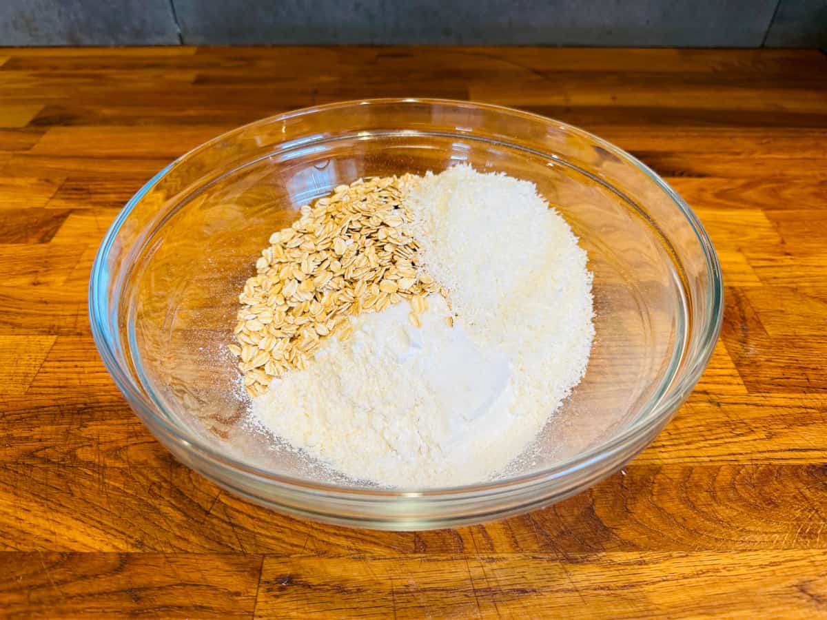 Glass bowl with oats, coconut, flour, and other dry ingredients.