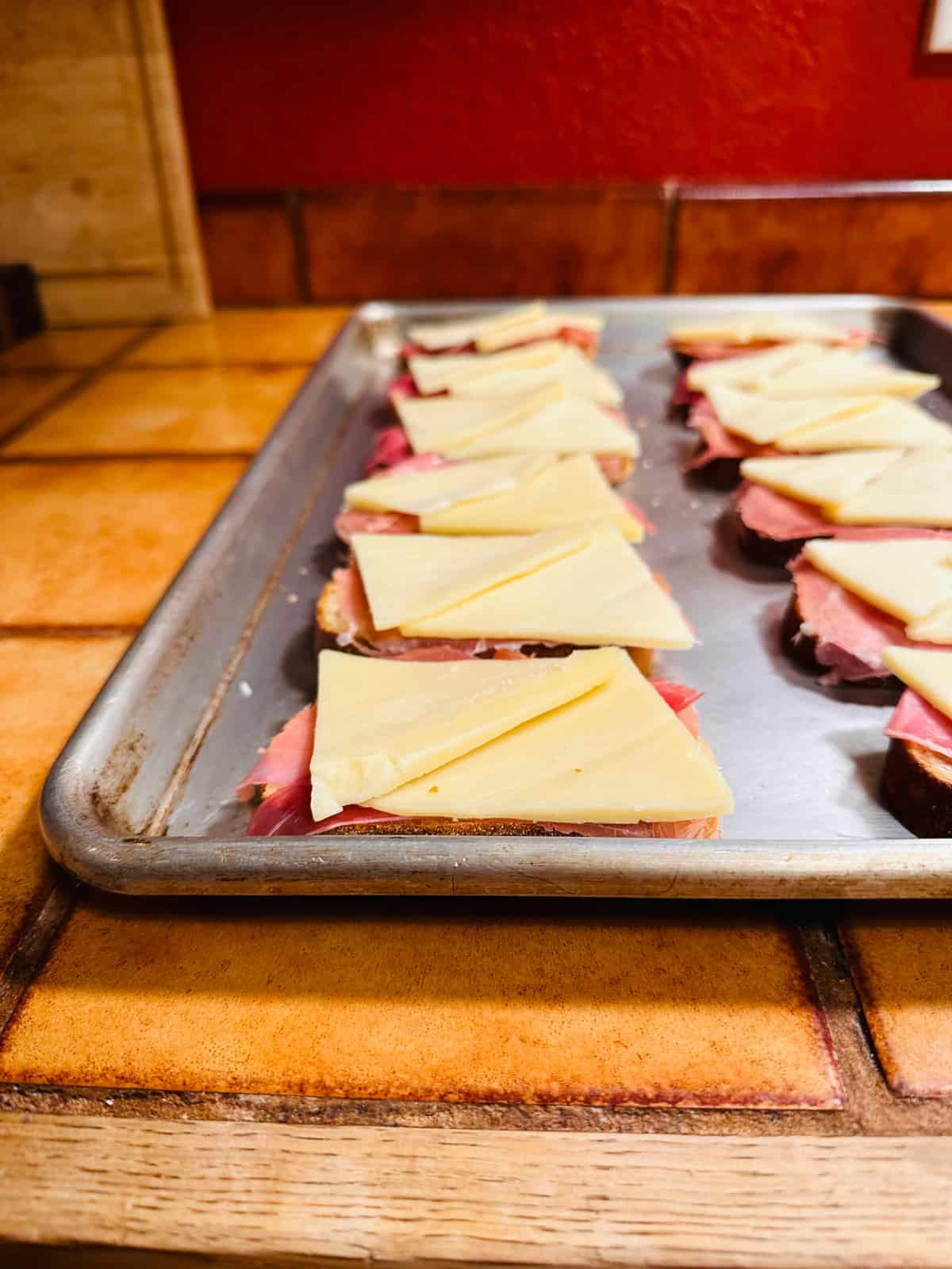 Metal baking sheet with uncooked toasts arranged in two rows.  