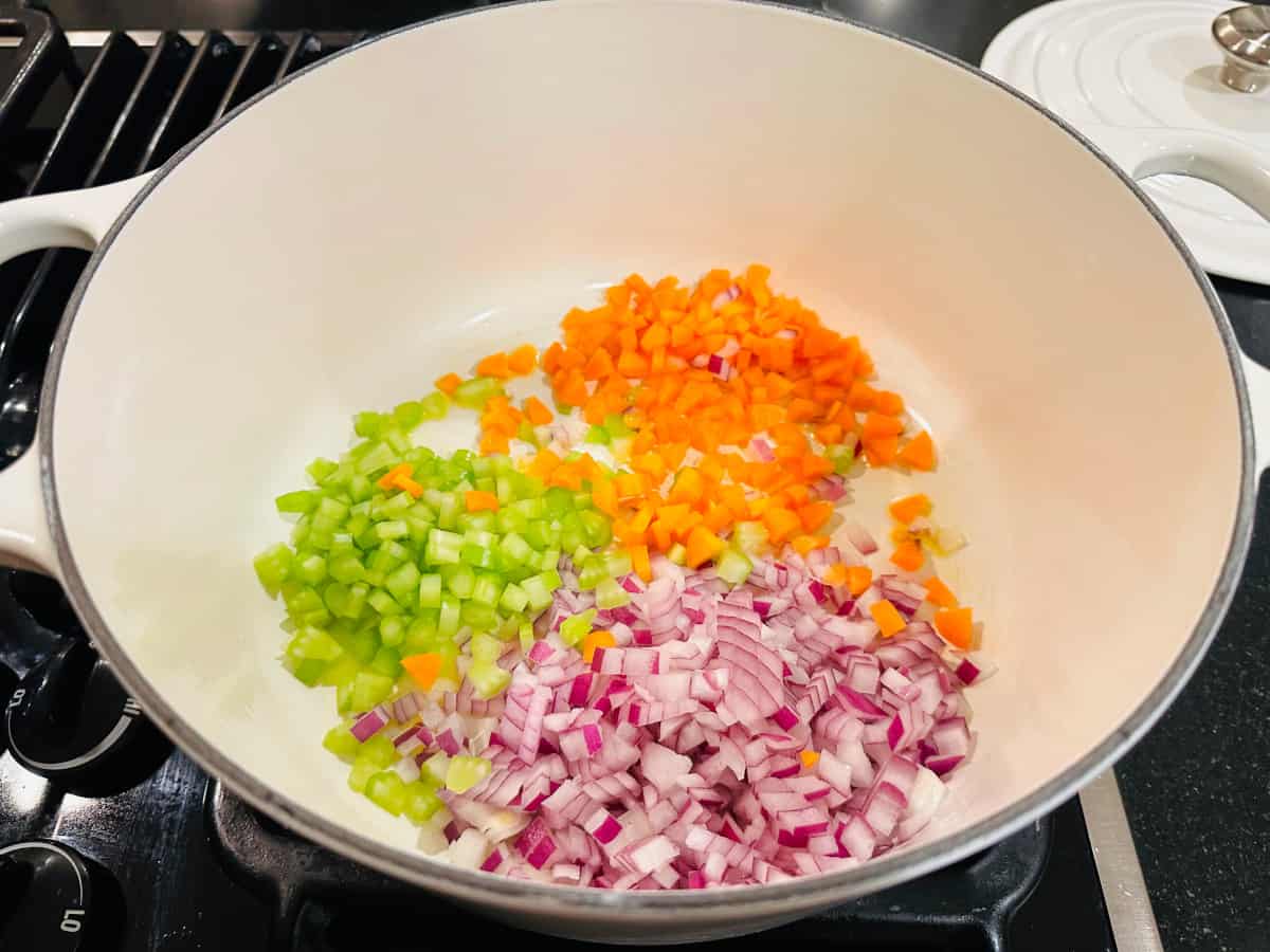 Chopped red onion, celery, and carrot in a white pot.