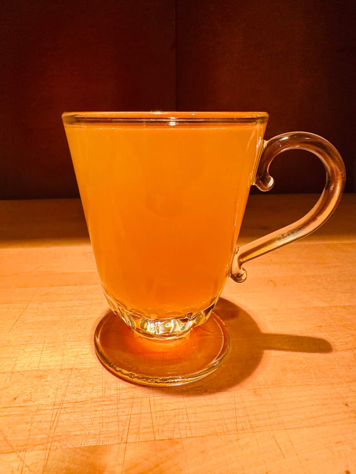 Golden colored whiskey hot toddy in a glass mug.