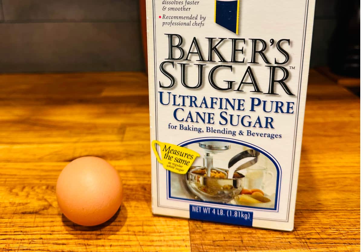 Brown egg next to a carton of caster sugar.