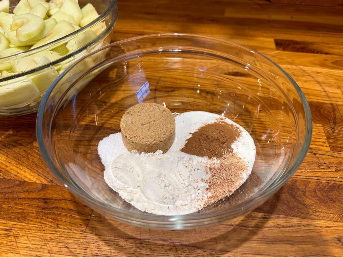 Flour, sugar, brown sugar, cinnamon, and nutmeg in a glass bowl.