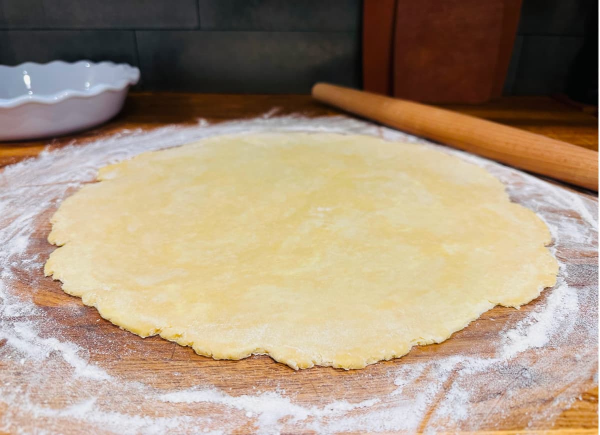 Large circle of pie dough rolled out on a floured surface.