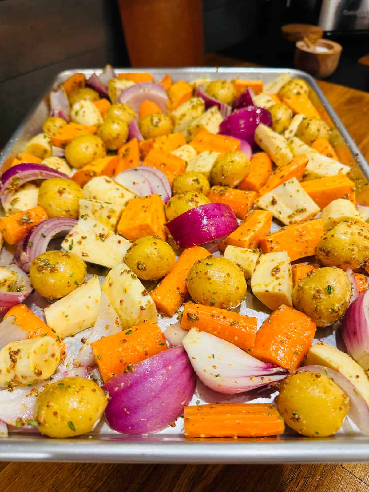 Mixed root vegetables coated with chicken seasoning and spread out on a baking sheet.