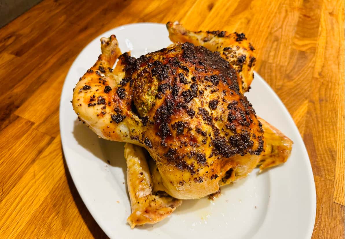 Whole roasted chicken on a white plate.