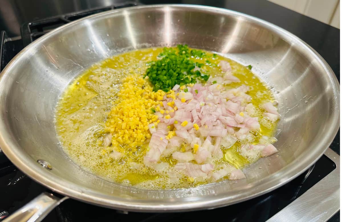 Chopped shallot, ginger, and jalapeno cooking in butter and olive oil in a large skillet.