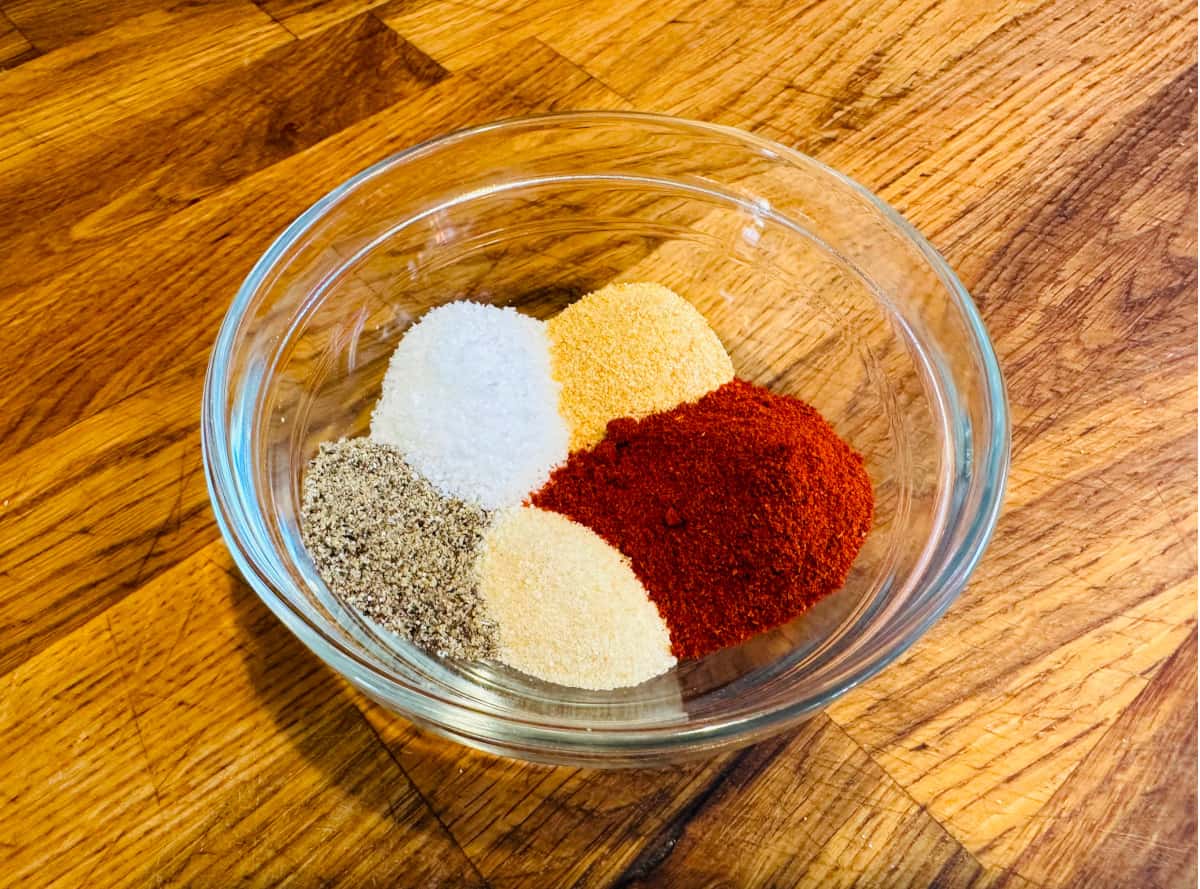 Paprika, onion powder, black pepper, salt, and garlic powder in a small glass bowl.