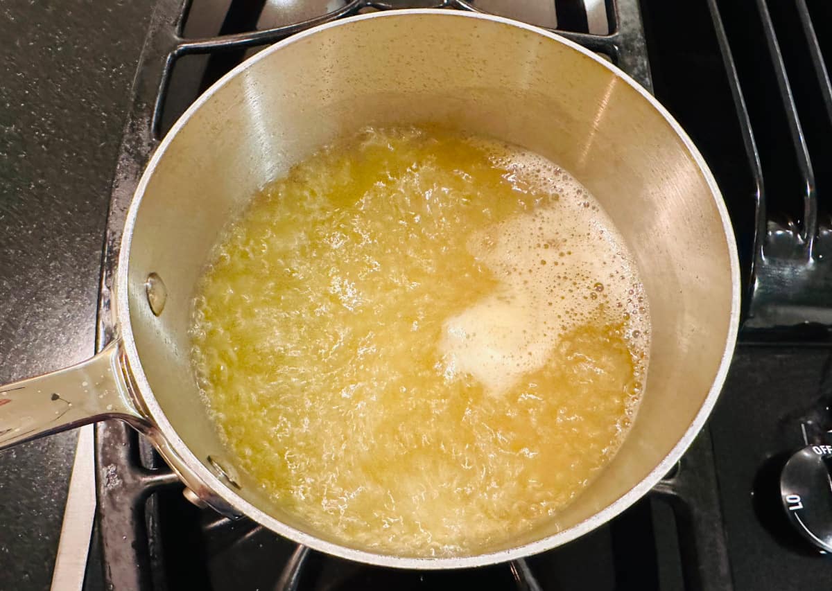 Chicken stock boiling in a metal saucepan on the stove.