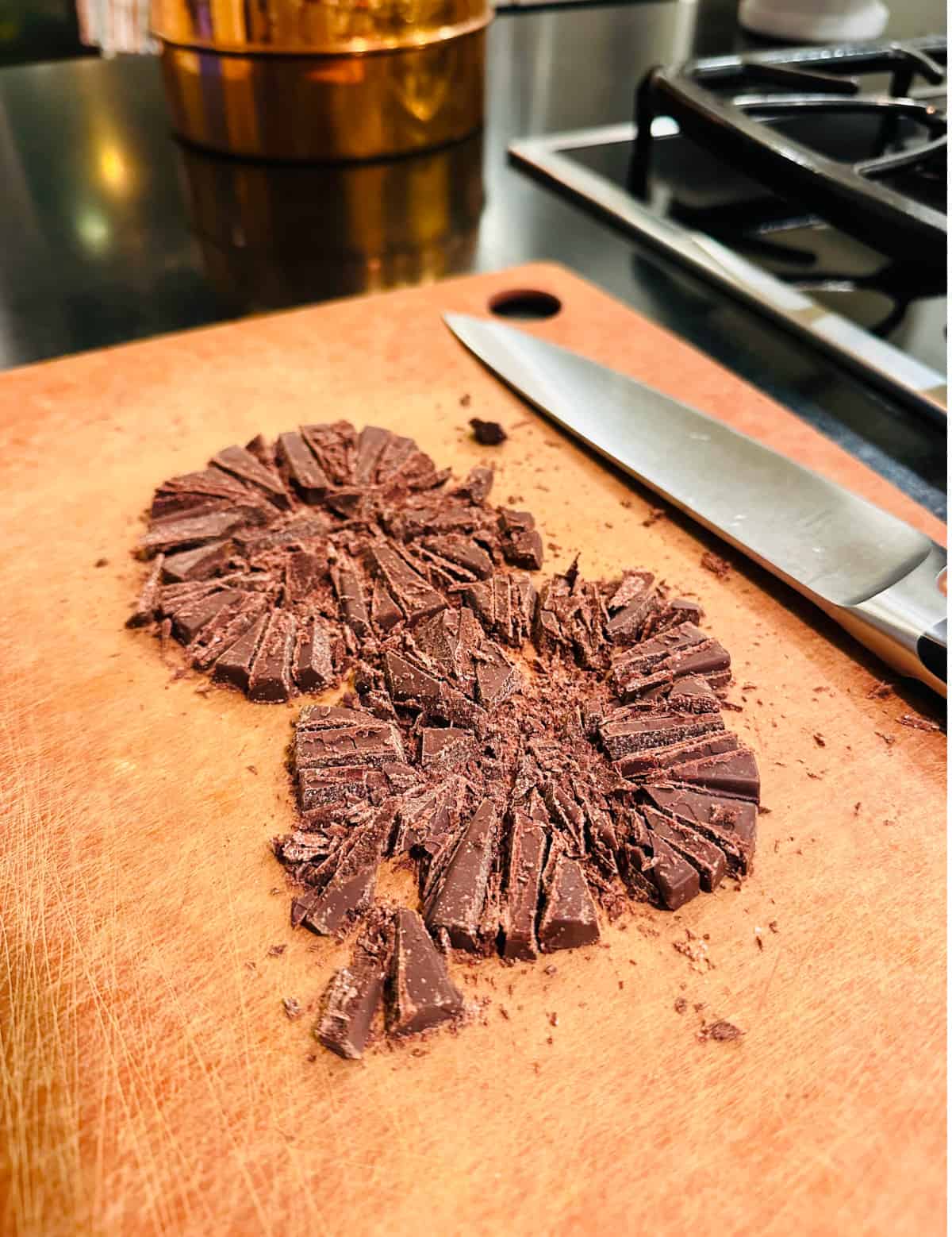 Chopped chocolate on a cutting board with a chef's knife.