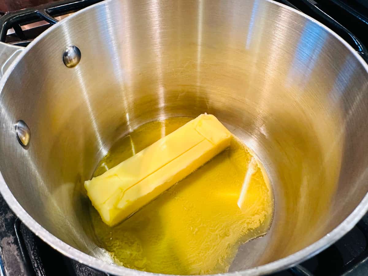 Stick of butter melting in a small metal saucepan.