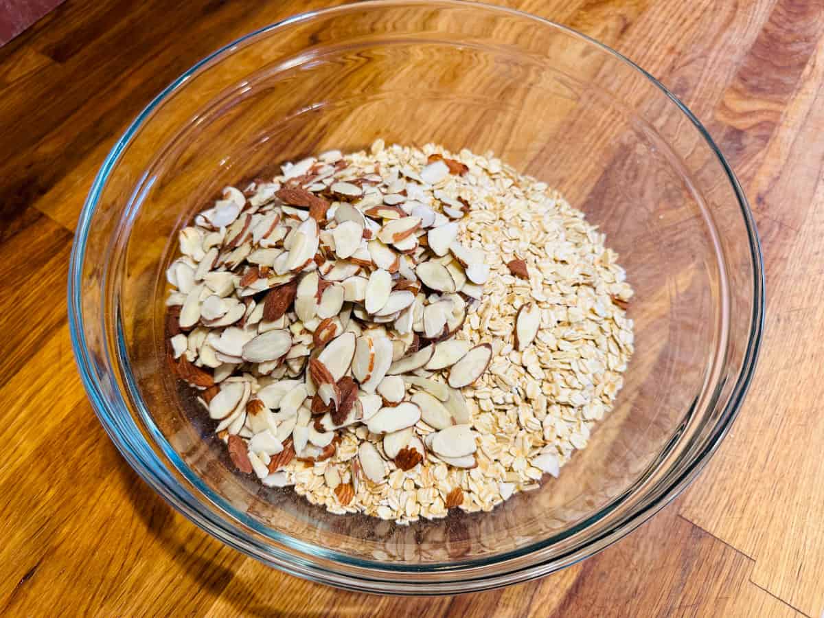 Rolled oats and sliced almonds in a glass bowl.