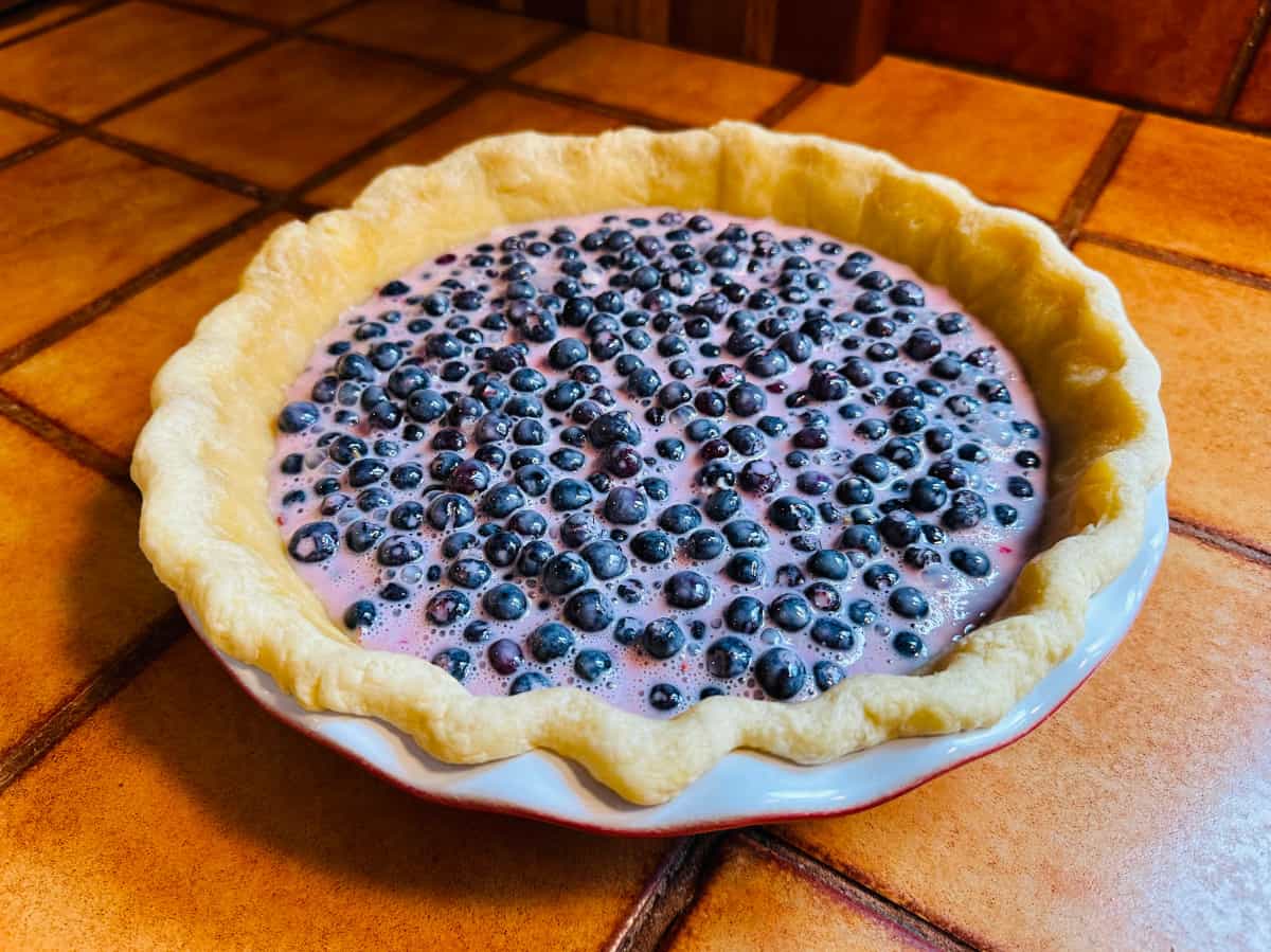 Blueberry filling poured into a partially baked pie crust.