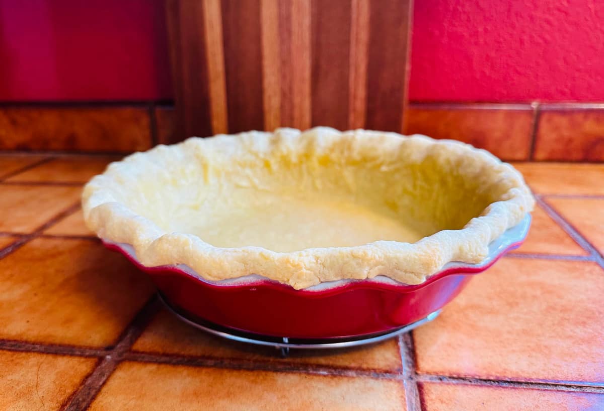Partially baked pie crust in a red pie plate.