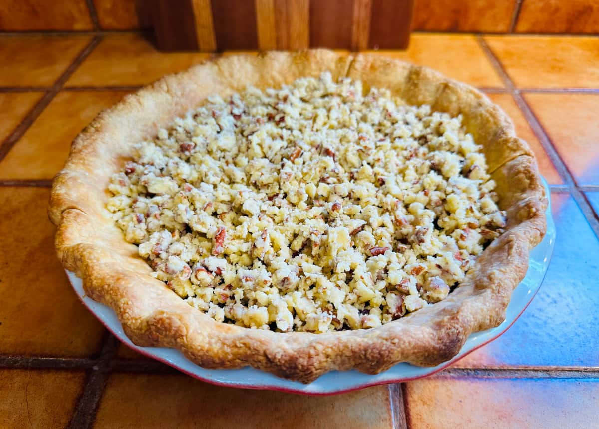 Unbaked crumble topping sprinkled on top of a partially baked pie.