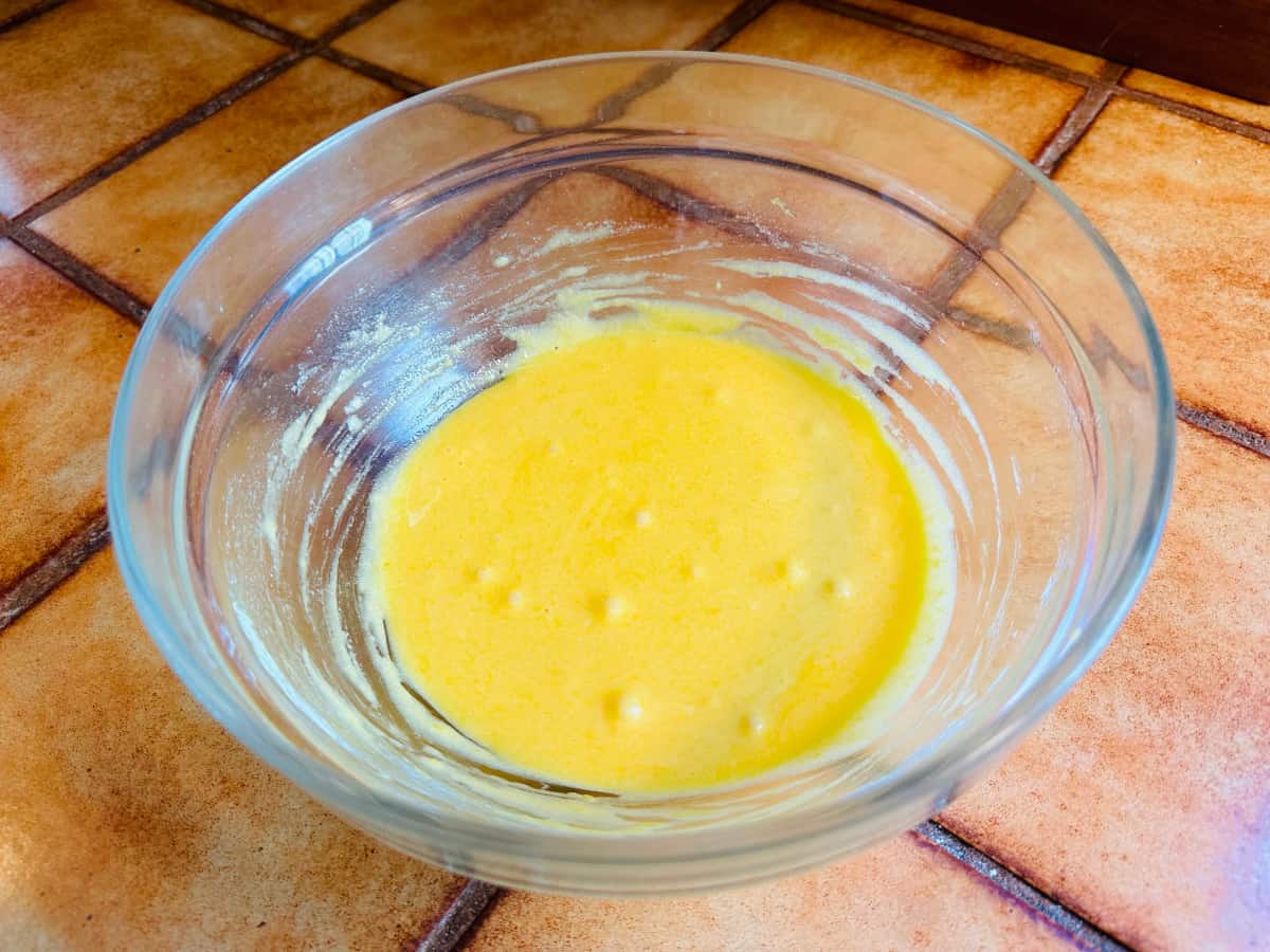 Pale yellow mixture of egg yolks, sugar, and flour in a glass bowl.