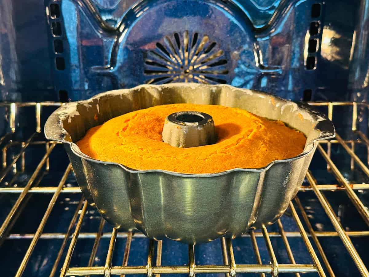 Golden brown bundt cake baking in a blue oven.