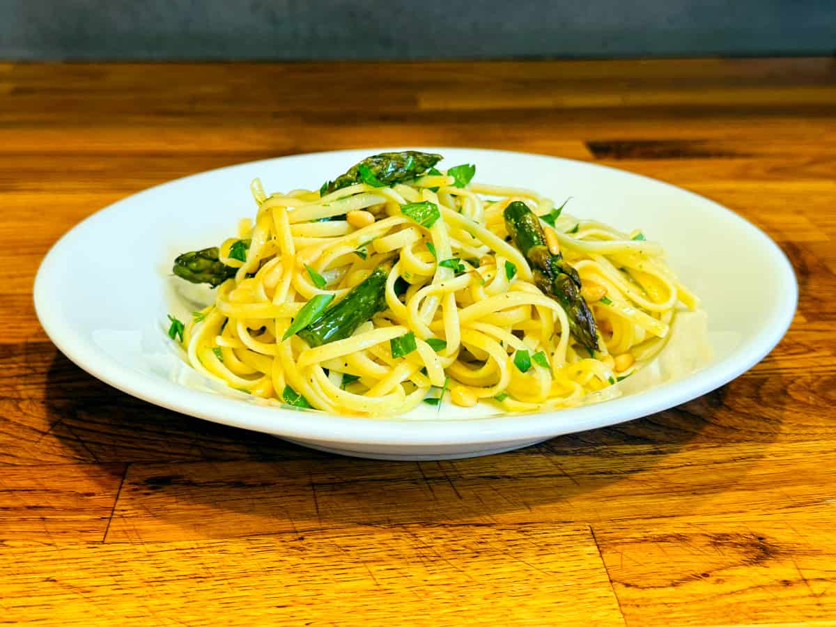 Lemon pasta with asparagus in a shallow white bowl.