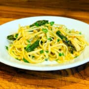 Lemon pasta with asparagus in a shallow white bowl.