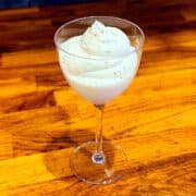 Billowy white layers of whipped cream in a small glass with grated nutmeg sprinkled on top.