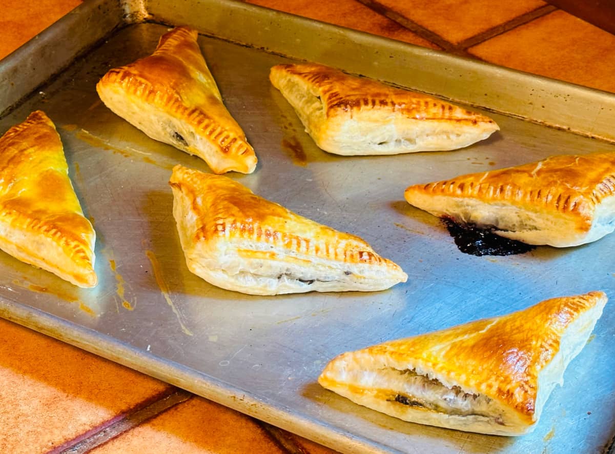 Baked blueberry turnovers on a metal baking sheet.