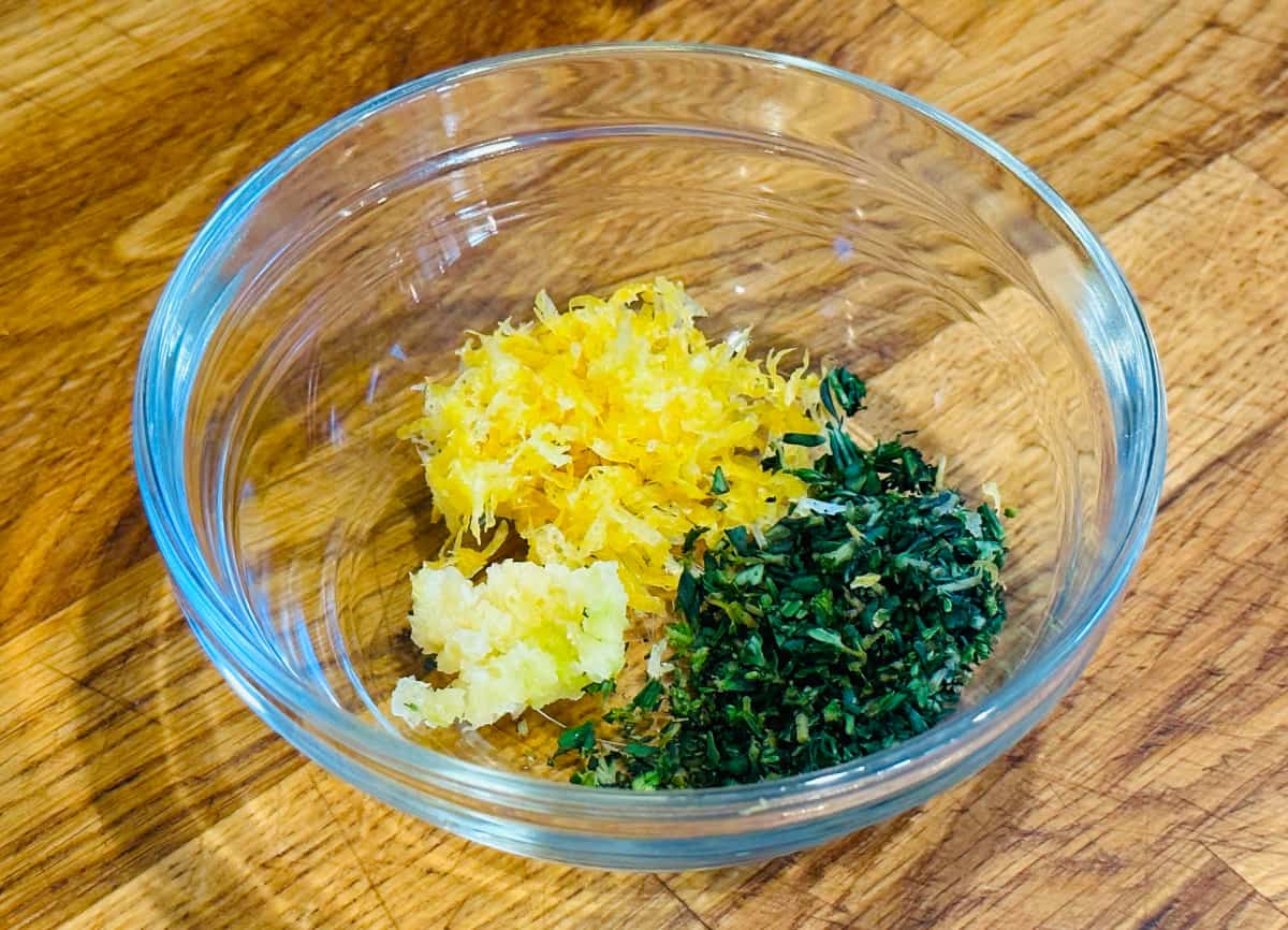 Lemon zest, chopped thyme, and grated garlic in a small glass bowl.
