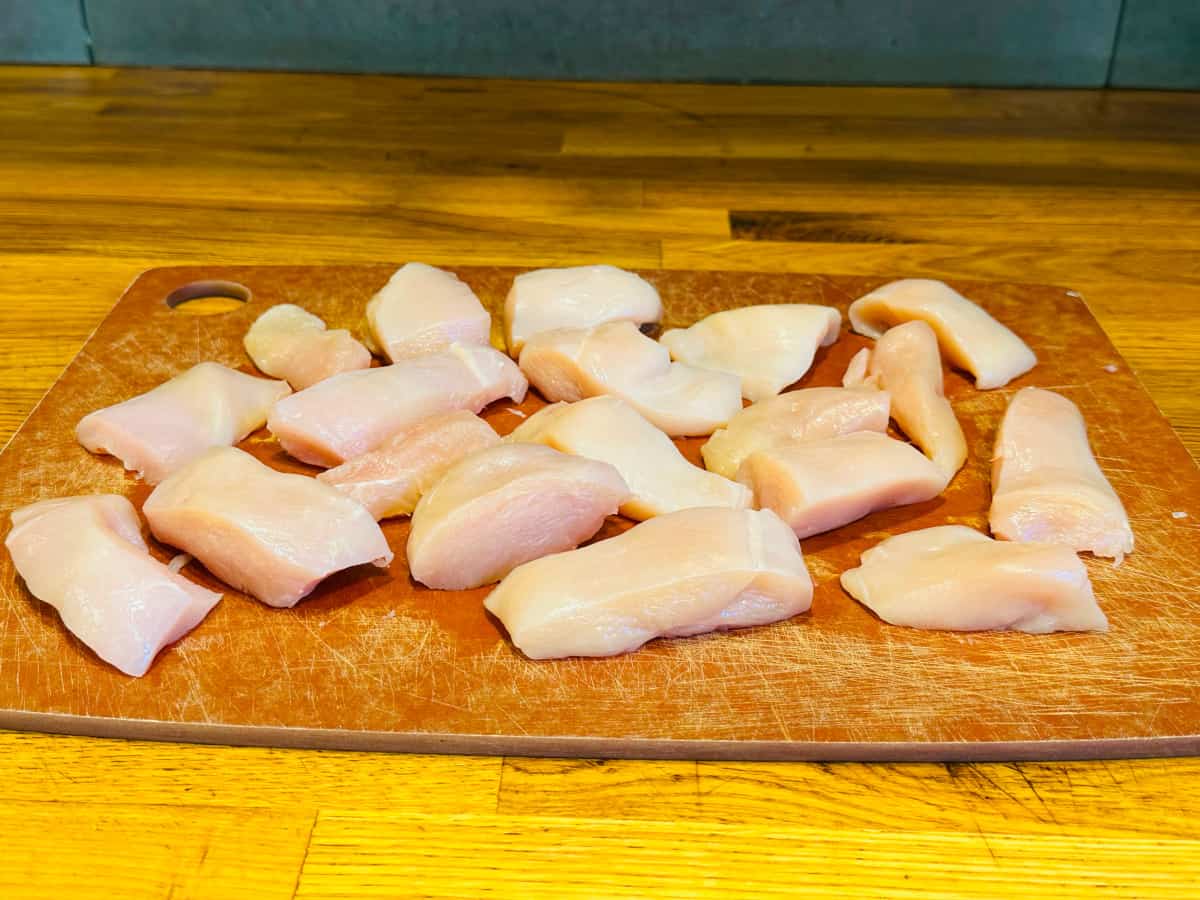 Medium sized chicken breast pieces on a wooden cutting board.