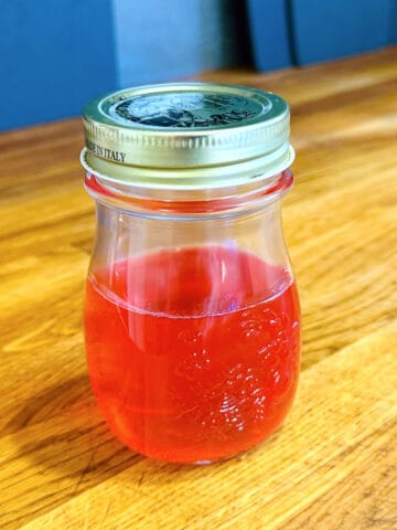 Peach simple syrup in a small bottle with a lid.