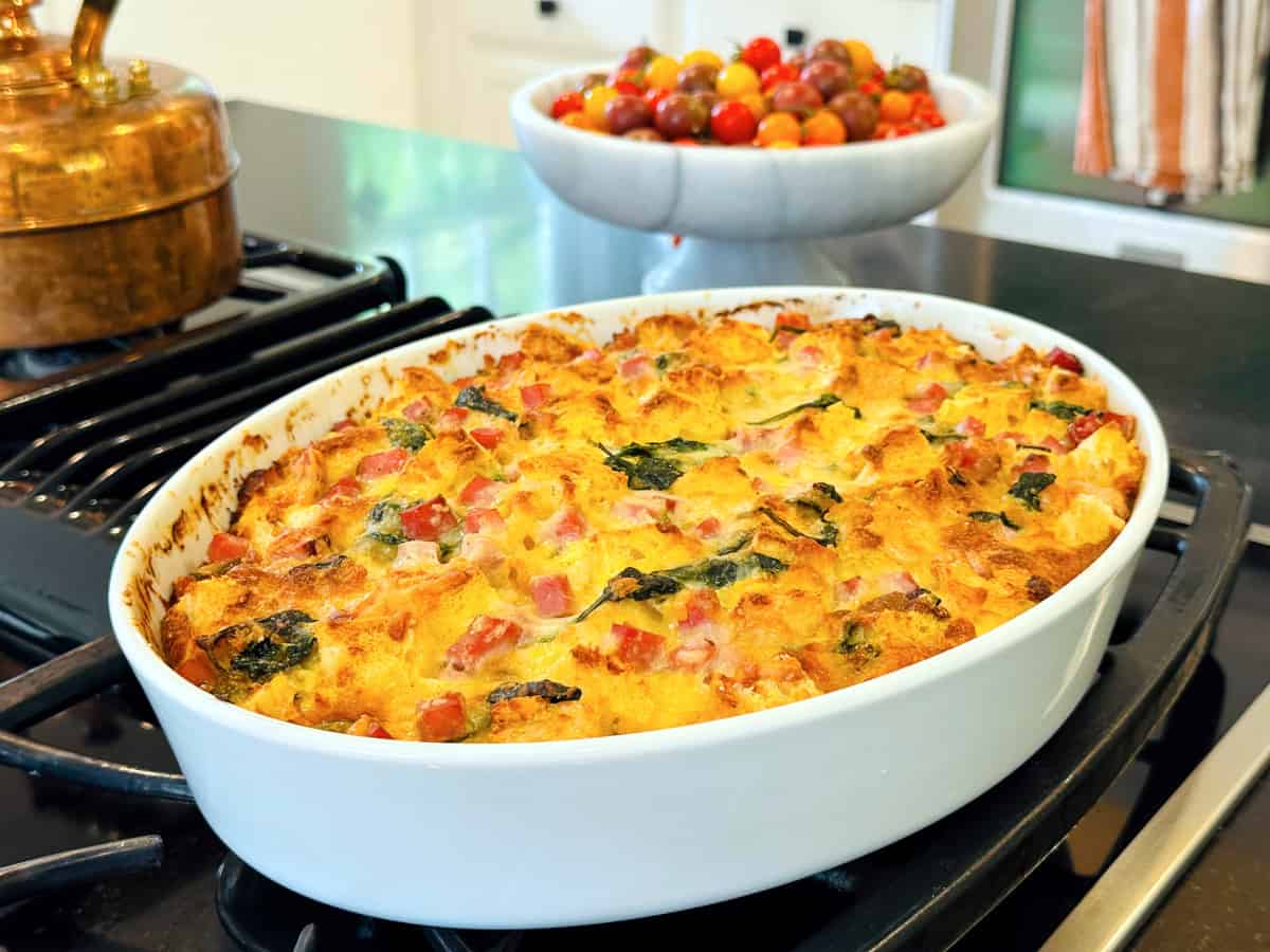 Breakfast strata in an oval white baking dish sitting on the stove.