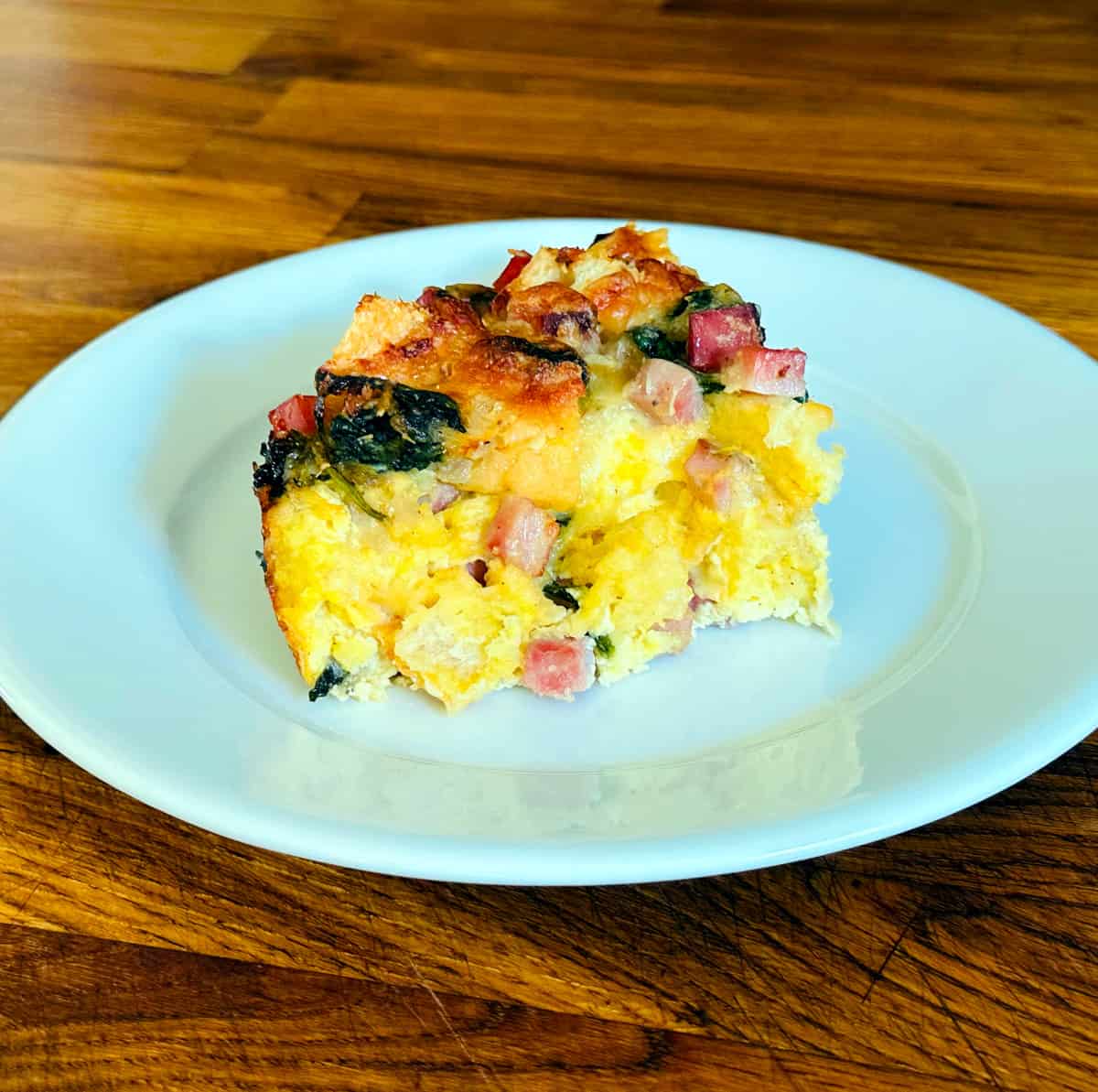 Breakfast strata on a small white plate.