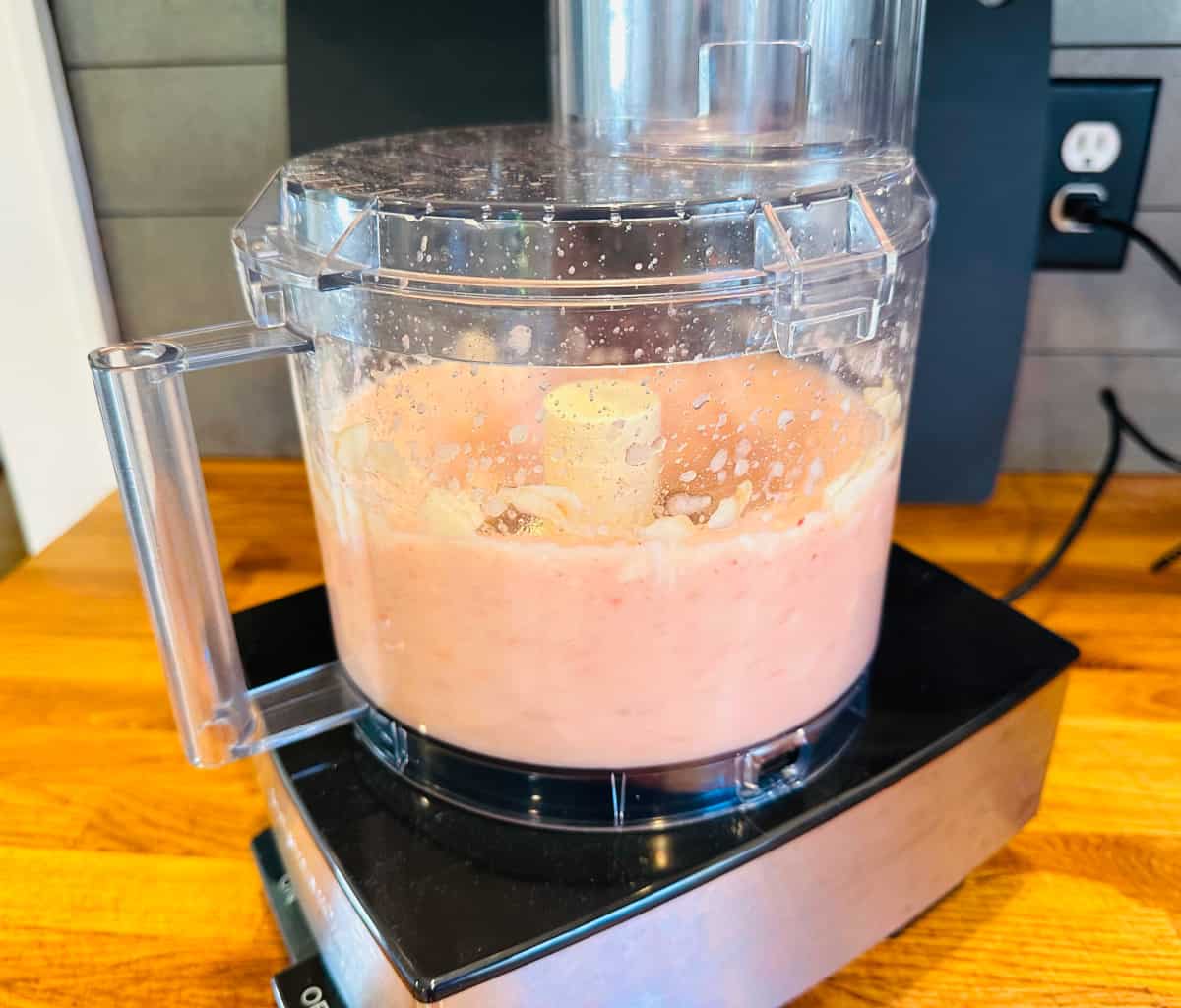 Pale pink purée being blended in a food processor.