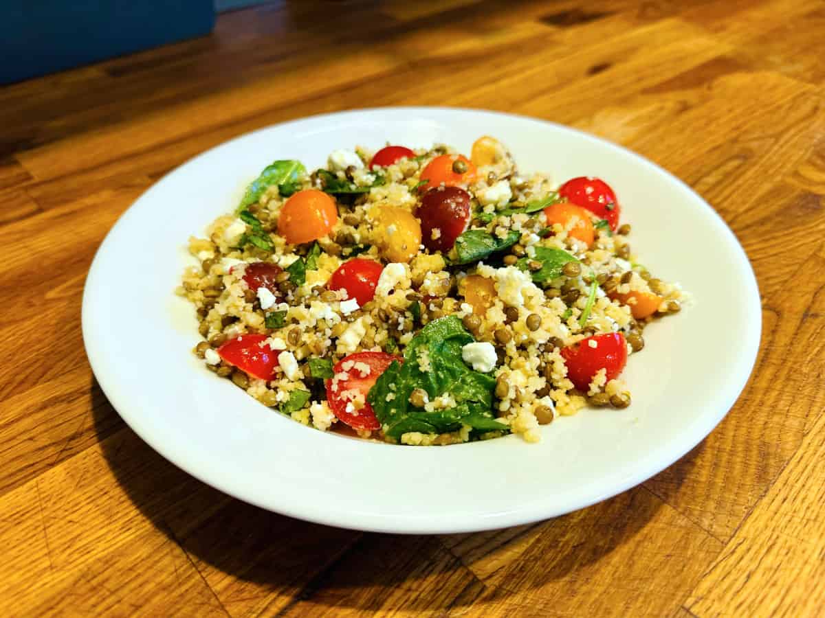 Mediterranean couscous and lentil salad served in a shallow white bowl.