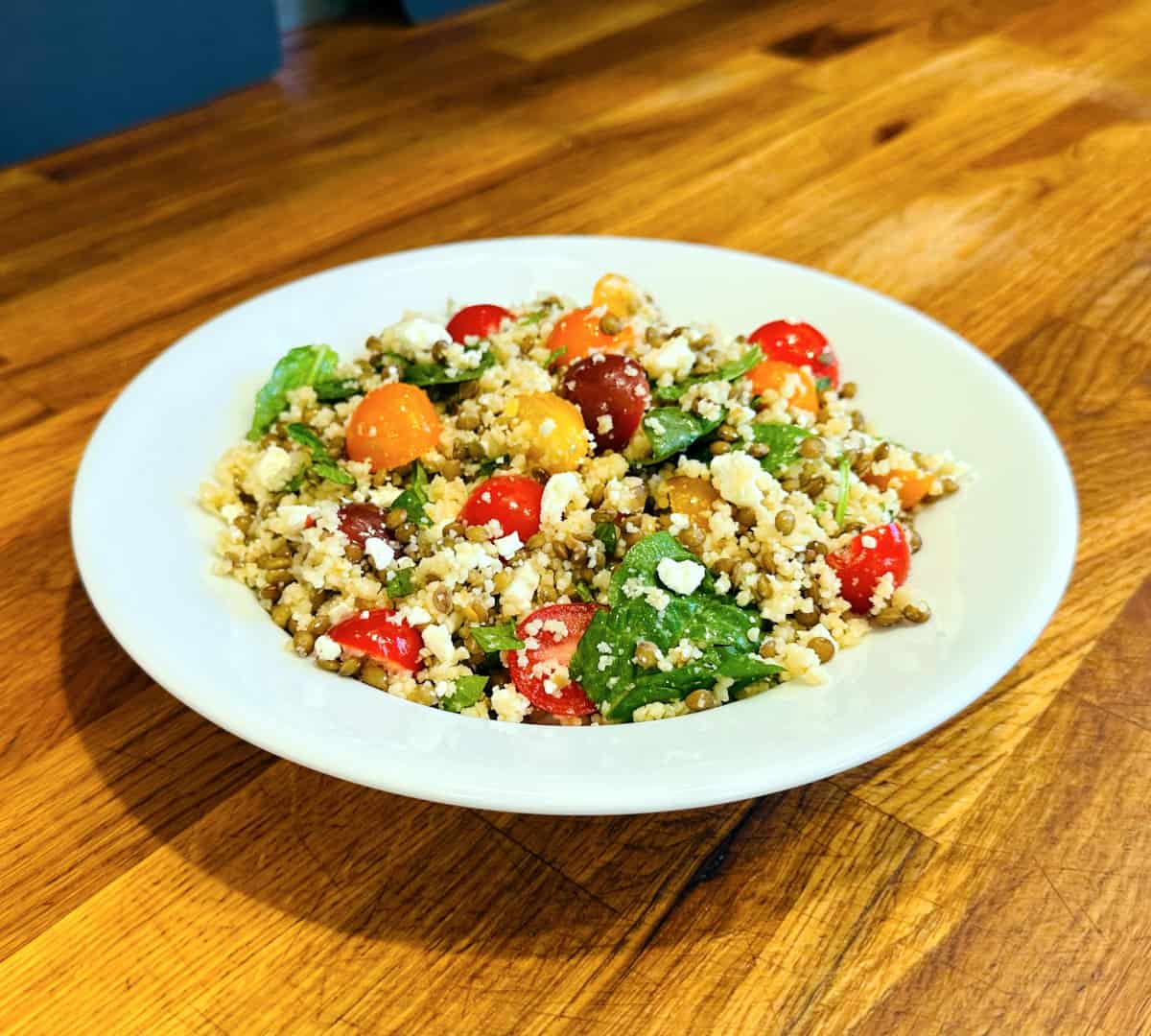 Mediterranean couscous and lentil salad served in a shallow white bowl.