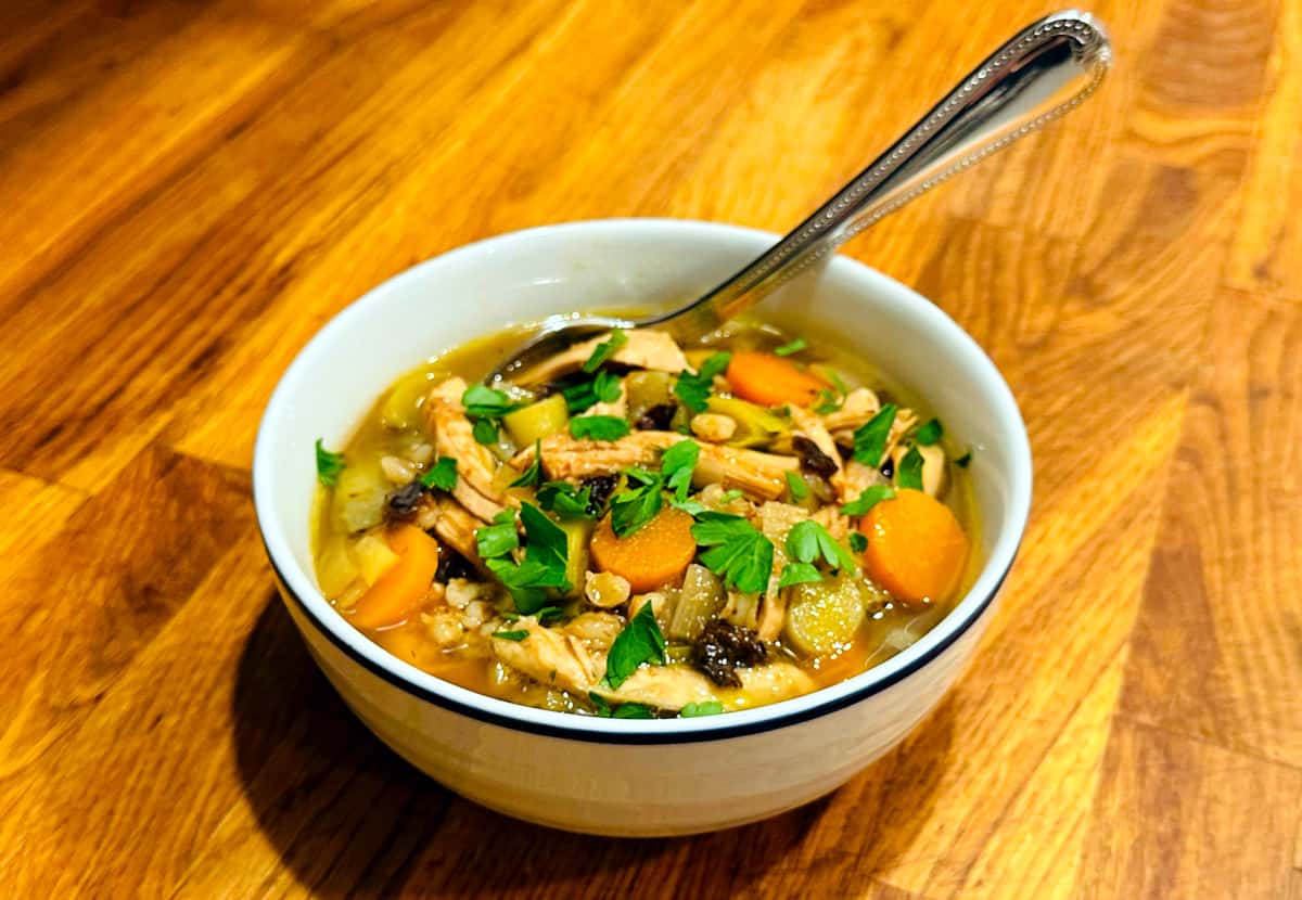 Cock-a-leekie soup in a white bowl with a navy stripe around the rim.