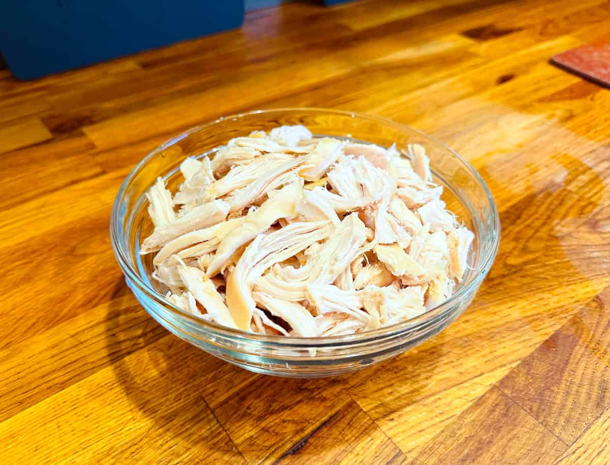 Shredded chicken breast in a glass bowl.