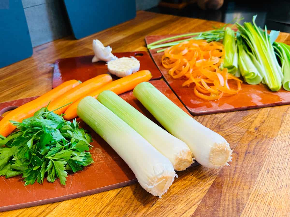 Parsley leaves, peeled carrots trimmed leeks, halved garlic head, carrot peels, leek tops, and parsley stems.