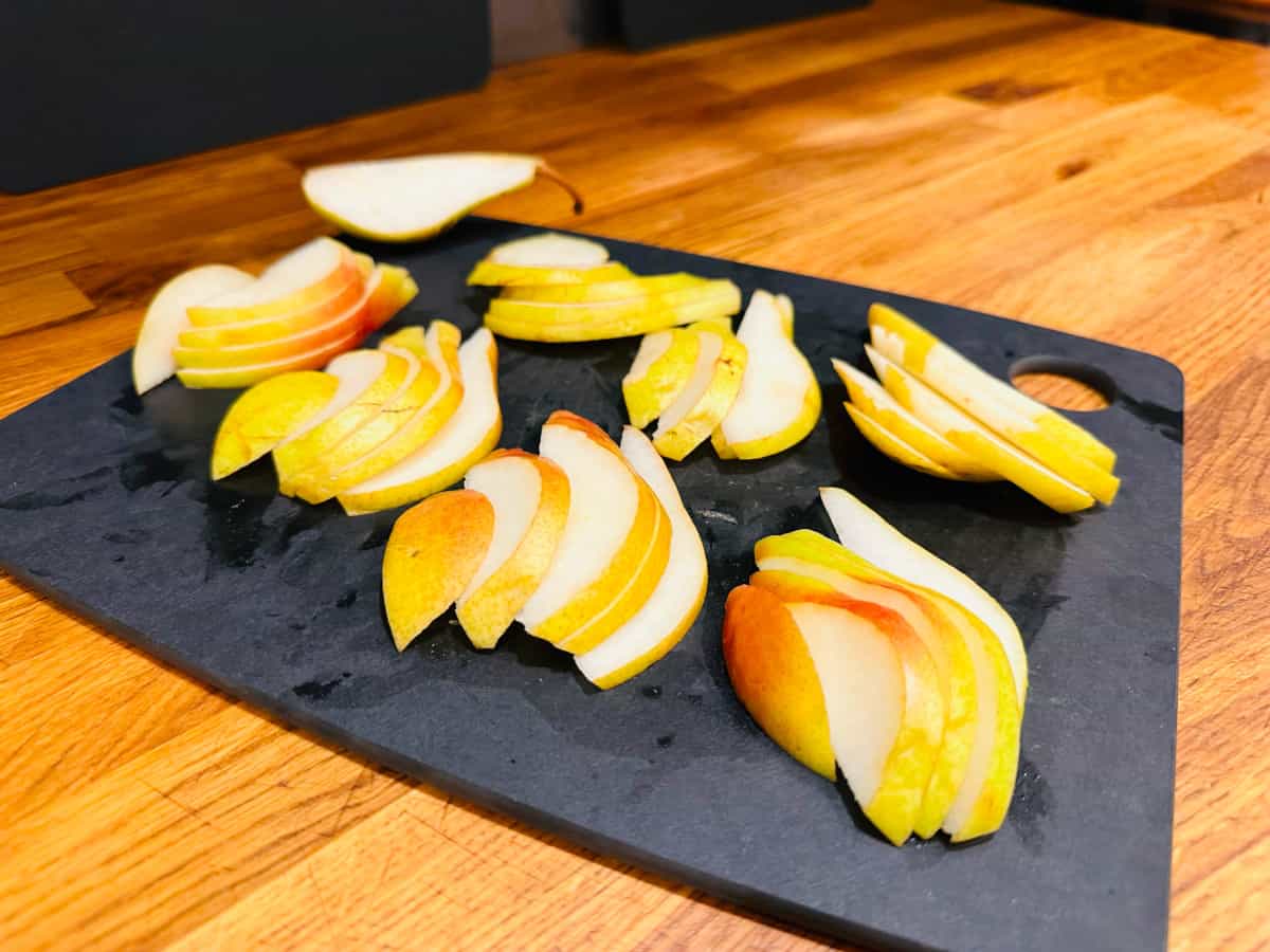 Sliced pears on a black cutting board.