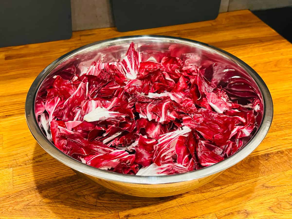 Torn radicchio leaves in a large metal bowl.