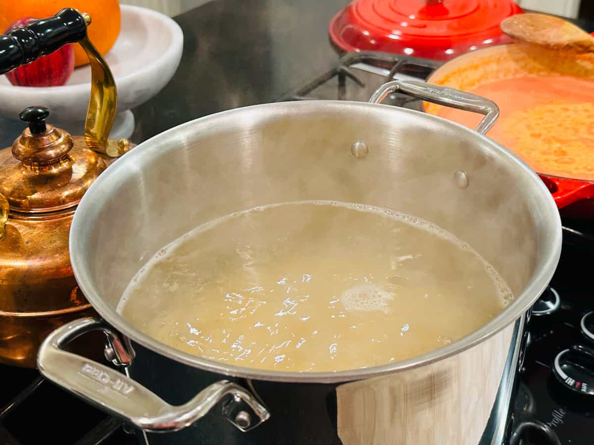Pasta cooking in boiling water in a large metal stockpot on the stove.
