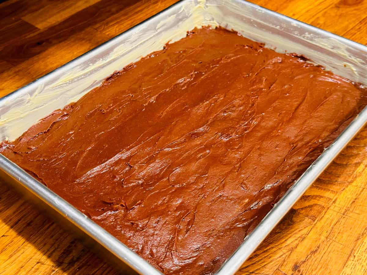 Brownie batter spread in a greased baking pan.