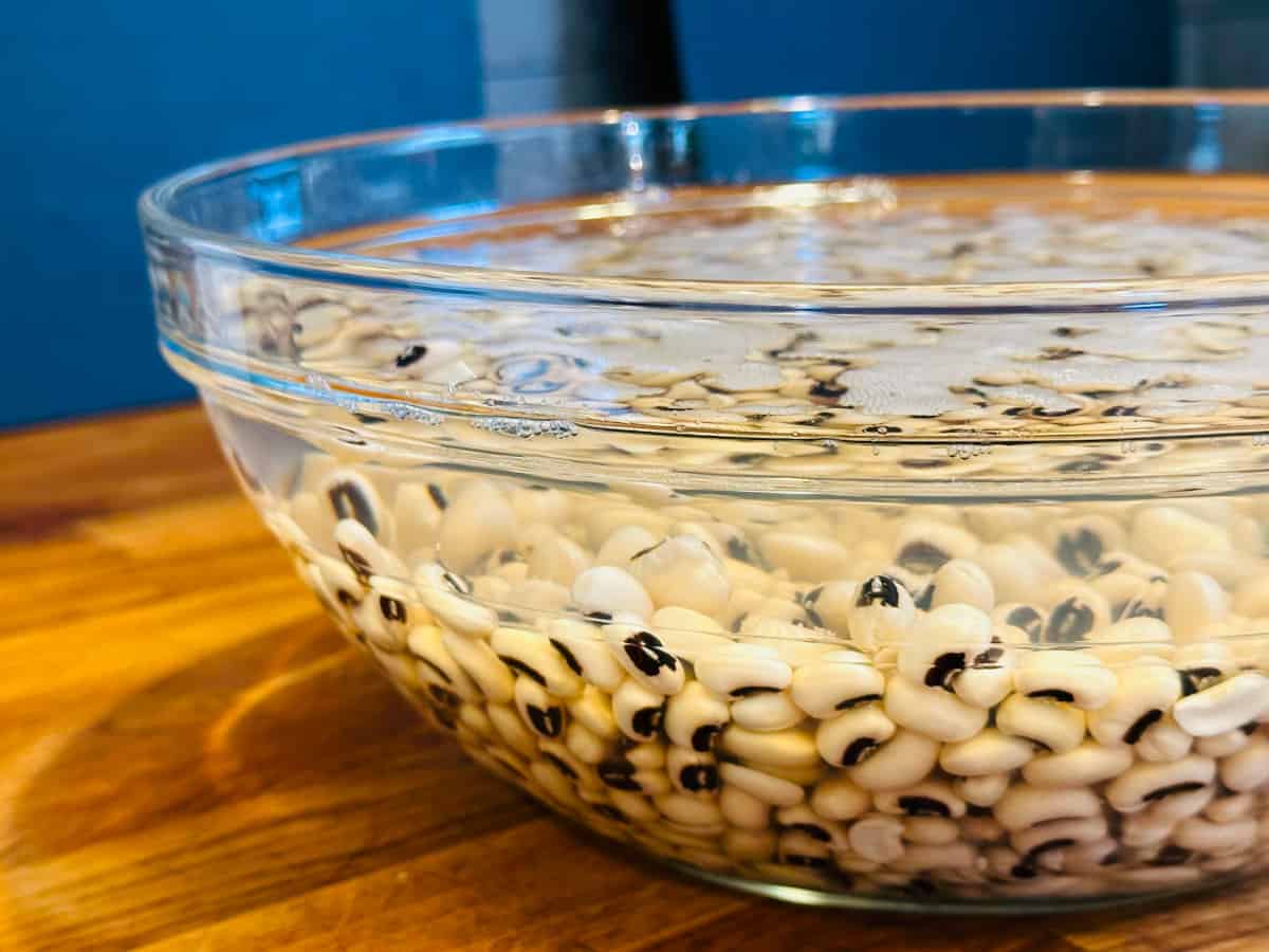 Black eyed pea soaking in water in a large glass bowl.