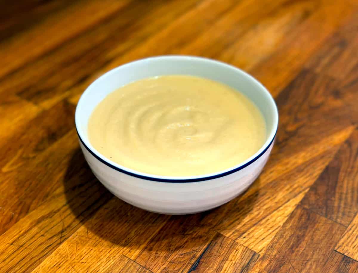 Parsnip soup in a white bowl with a blue rim.